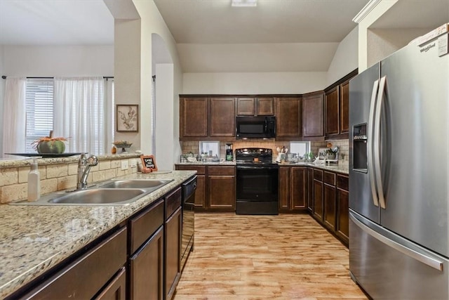 kitchen with sink, vaulted ceiling, decorative backsplash, black appliances, and light wood-type flooring