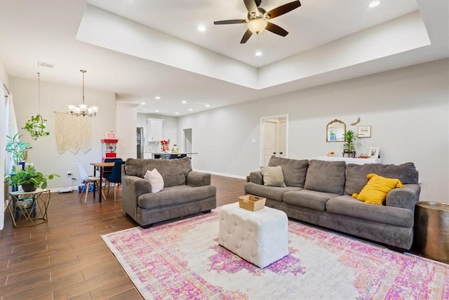 living room with ceiling fan with notable chandelier and dark wood-type flooring