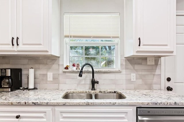 kitchen featuring decorative backsplash, sink, white cabinets, and stainless steel dishwasher