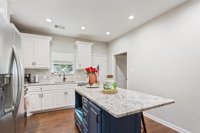 kitchen with blue cabinetry, stainless steel fridge, a center island, and white cabinets