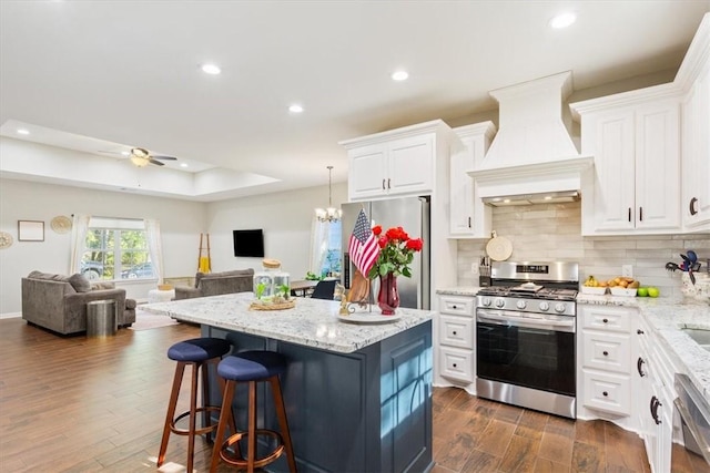 kitchen with premium range hood, stainless steel appliances, white cabinets, dark hardwood / wood-style floors, and a kitchen island