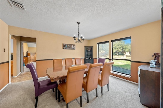 dining area with a notable chandelier, light colored carpet, and a textured ceiling