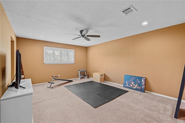 workout area featuring a textured ceiling, carpet floors, and ceiling fan