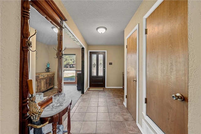 entryway with light tile patterned floors and a textured ceiling