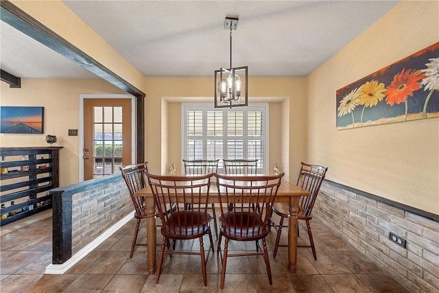 dining room with a chandelier and brick wall