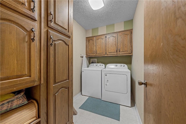 washroom featuring washer and clothes dryer, cabinets, and a textured ceiling