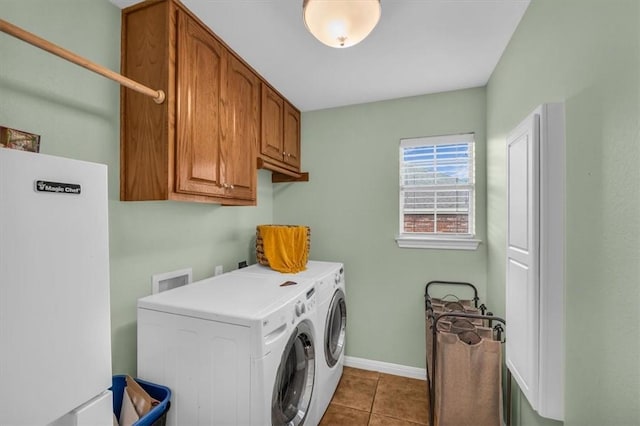 clothes washing area featuring cabinets, washing machine and dryer, and light tile patterned floors