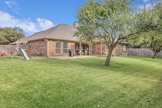 rear view of property featuring a yard and a playground