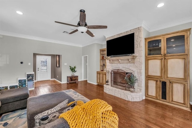 living room with crown molding, a fireplace, ceiling fan, and dark wood-type flooring