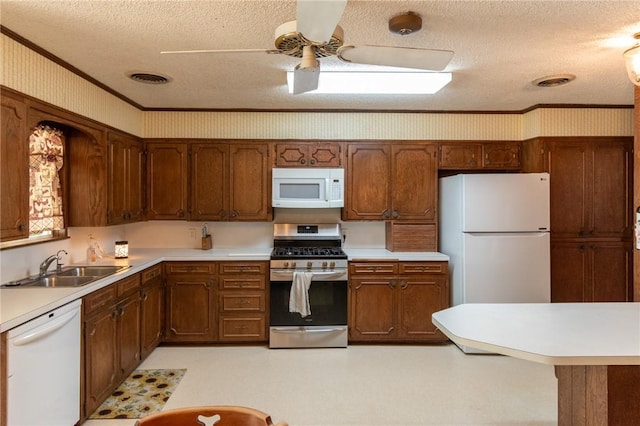 kitchen featuring white appliances, light countertops, wallpapered walls, and brown cabinetry