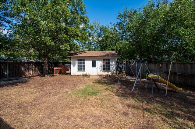 exterior space featuring an outbuilding, a playground, stucco siding, a lawn, and a fenced backyard