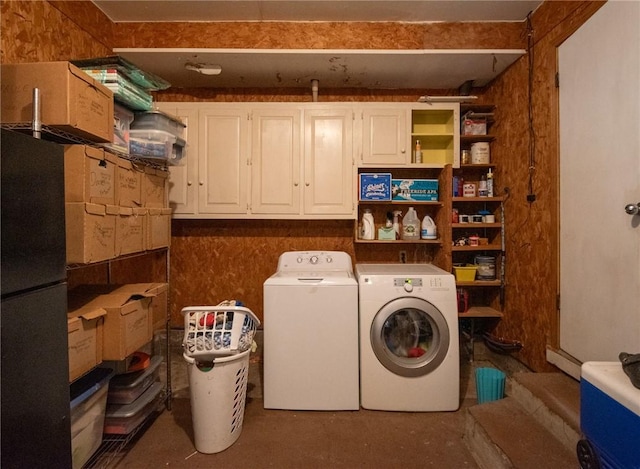 clothes washing area with separate washer and dryer and cabinet space