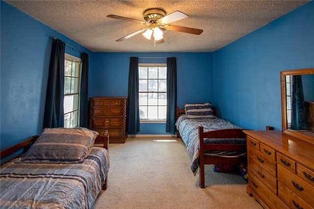 bedroom with ceiling fan, multiple windows, a textured ceiling, and light colored carpet