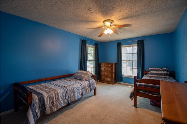 bedroom with light carpet, ceiling fan, baseboards, and a textured ceiling