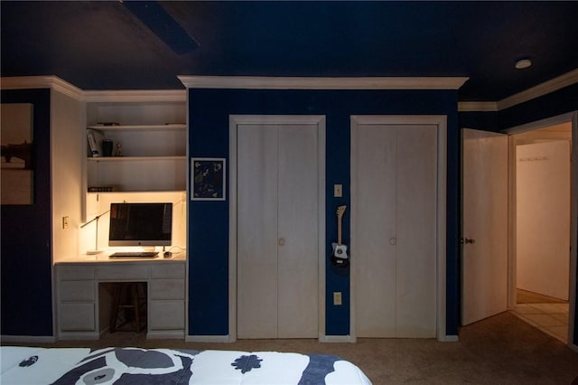 unfurnished bedroom featuring ornamental molding, carpet, two closets, and built in desk