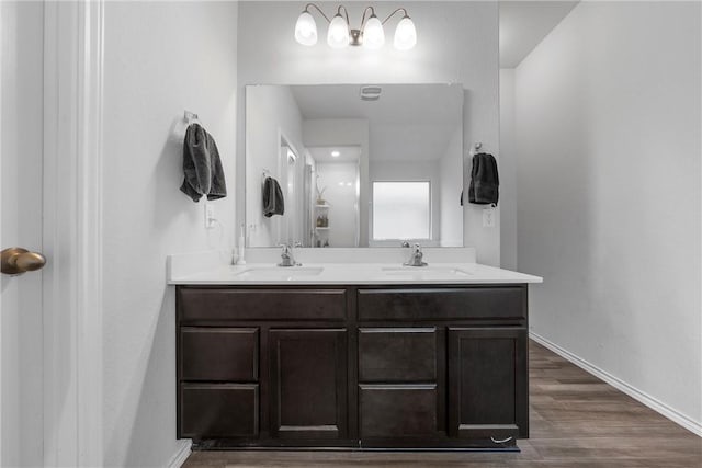 bathroom featuring double vanity, a sink, baseboards, and wood finished floors