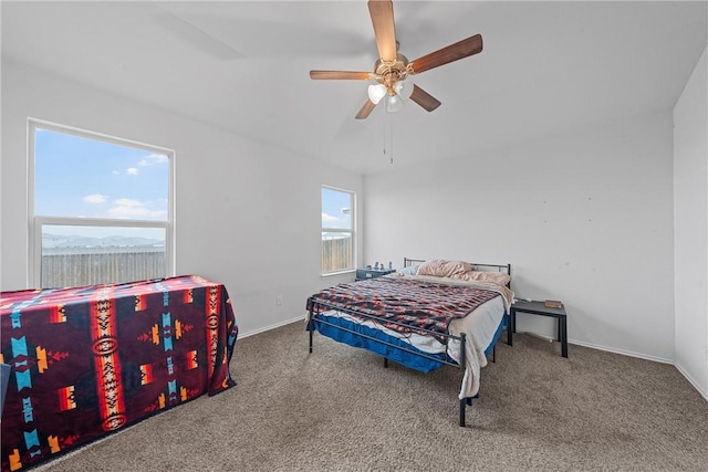 carpeted bedroom with ceiling fan, multiple windows, and baseboards