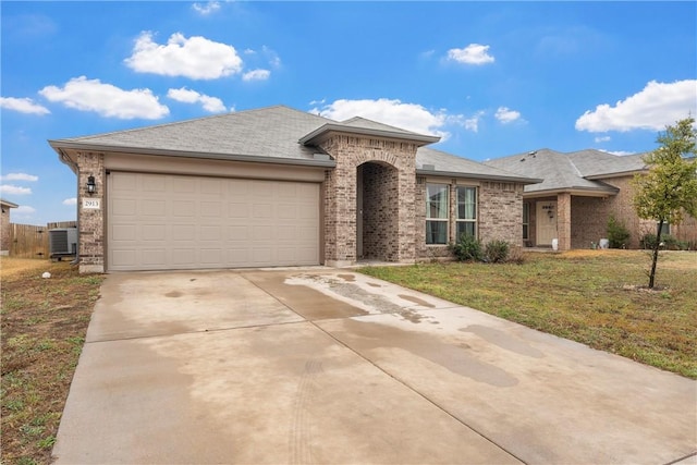 view of front of house with brick siding, an attached garage, cooling unit, driveway, and a front lawn