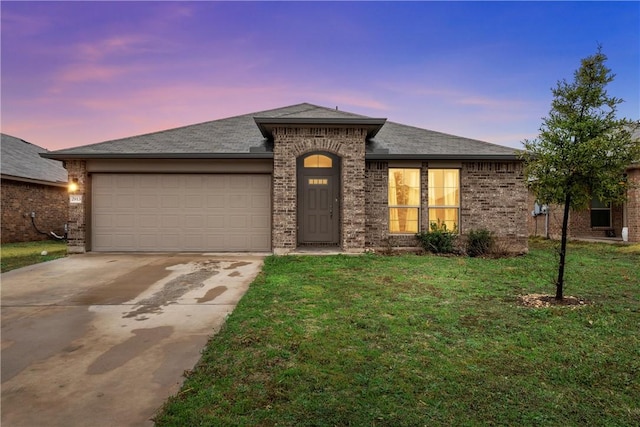 view of front of home with driveway, a shingled roof, an attached garage, a front lawn, and brick siding