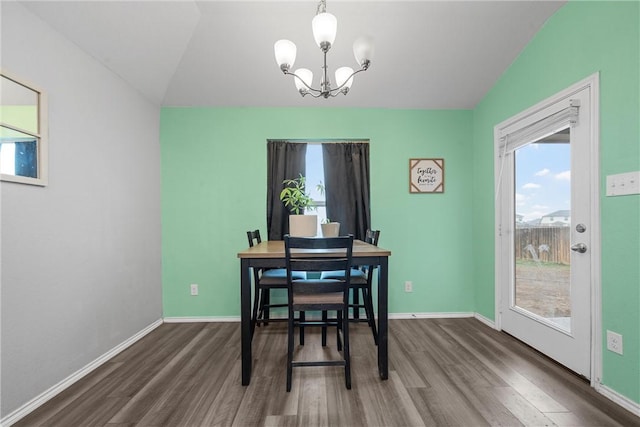 dining space with a chandelier, vaulted ceiling, baseboards, and wood finished floors