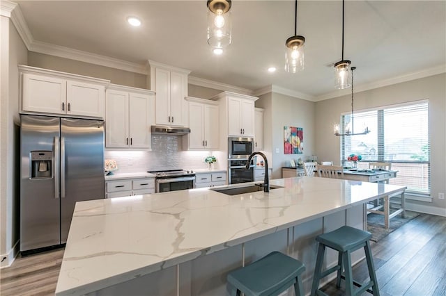 kitchen with stainless steel appliances, white cabinetry, hanging light fixtures, and sink