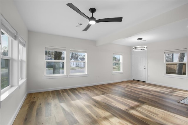 spare room featuring ceiling fan, wood-type flooring, and plenty of natural light