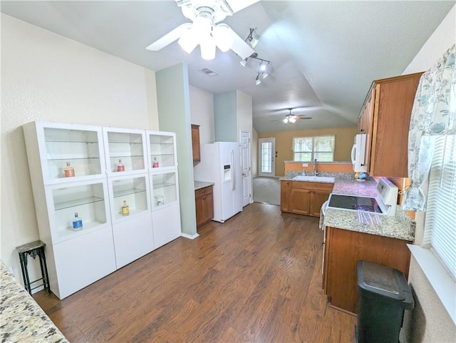 kitchen with kitchen peninsula, white appliances, vaulted ceiling, sink, and dark hardwood / wood-style floors