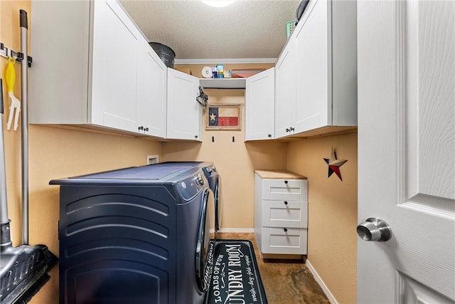 clothes washing area with cabinets, a textured ceiling, and washer and dryer