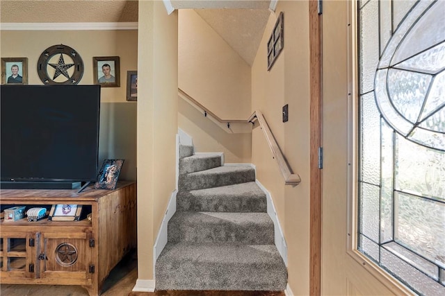 stairway with a textured ceiling and crown molding