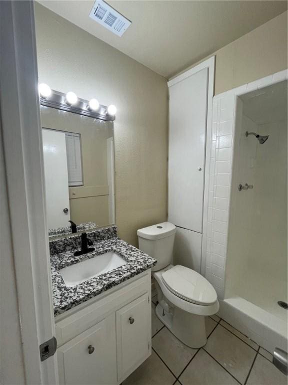 bathroom with vanity, a tile shower, tile patterned floors, and toilet