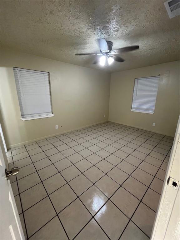 tiled spare room with a textured ceiling and ceiling fan