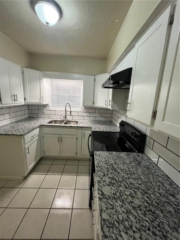 kitchen featuring sink, light tile patterned floors, white cabinetry, backsplash, and black electric range