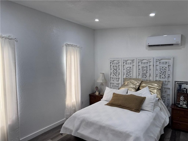 bedroom with a wall mounted AC and dark wood-type flooring