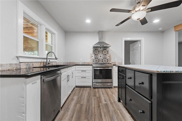 kitchen with white cabinetry, sink, light hardwood / wood-style floors, stainless steel appliances, and wall chimney exhaust hood