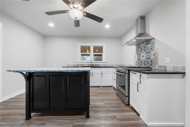 kitchen with white cabinets, dark hardwood / wood-style floors, wall chimney range hood, and stainless steel gas range