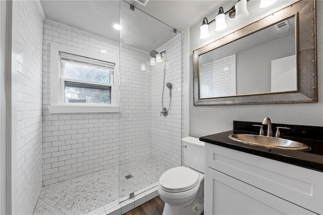 bathroom with tiled shower, vanity, toilet, and wood-type flooring