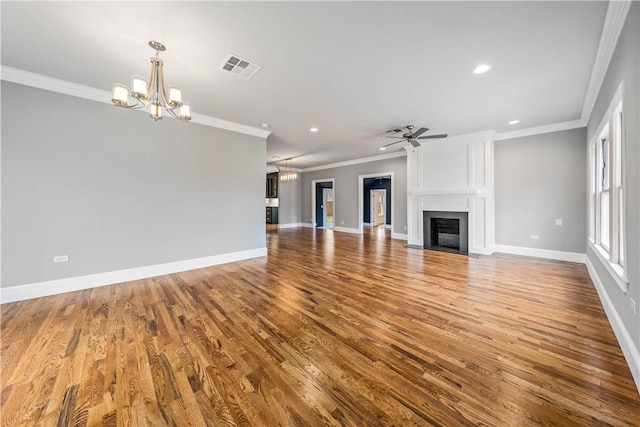 unfurnished living room featuring ceiling fan with notable chandelier, a large fireplace, wood-type flooring, and ornamental molding