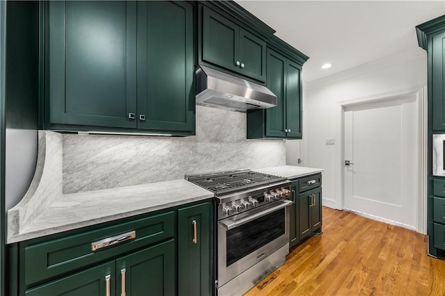 kitchen with decorative backsplash, light wood-type flooring, high end stainless steel range oven, and green cabinetry