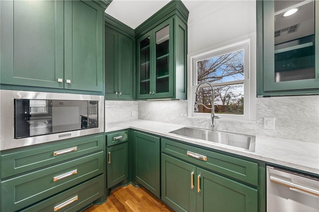 kitchen with light hardwood / wood-style floors, sink, appliances with stainless steel finishes, and green cabinetry