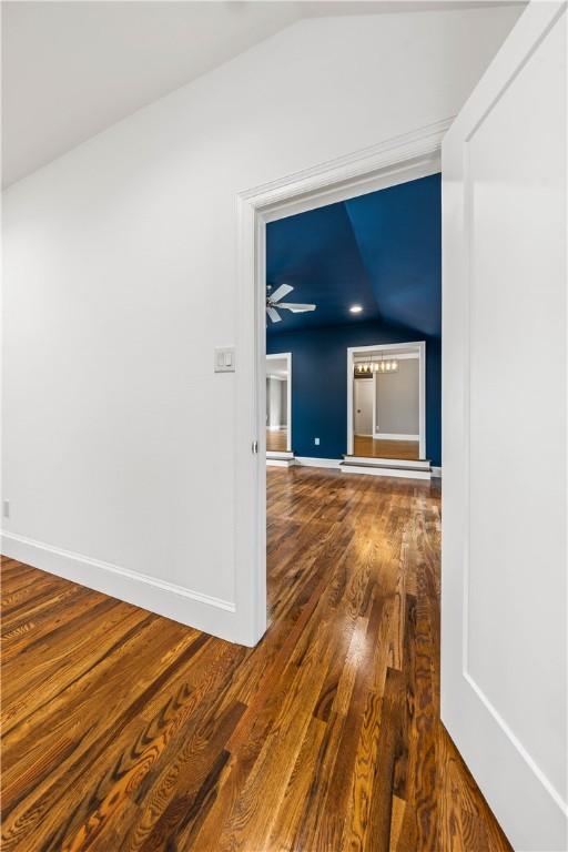 hallway with dark hardwood / wood-style flooring and vaulted ceiling