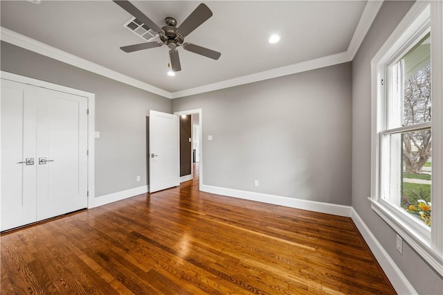 unfurnished bedroom with hardwood / wood-style flooring, multiple windows, crown molding, and ceiling fan