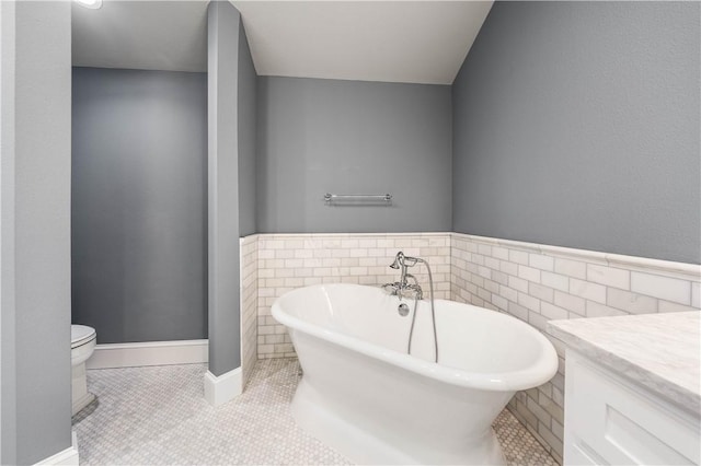 bathroom with tile patterned flooring, a bathtub, toilet, and tile walls