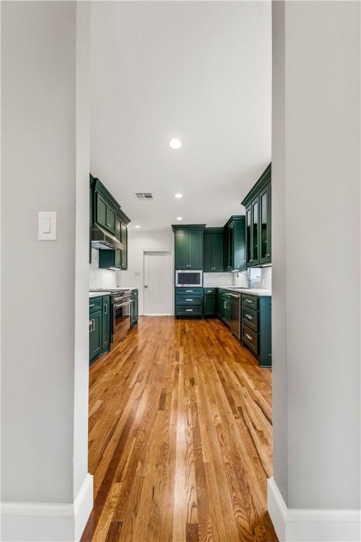 kitchen featuring appliances with stainless steel finishes, light hardwood / wood-style flooring, and green cabinetry