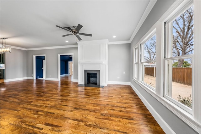 unfurnished living room with hardwood / wood-style floors, a fireplace, crown molding, and ceiling fan with notable chandelier