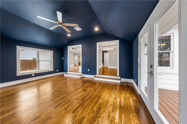 unfurnished bedroom featuring hardwood / wood-style flooring, ceiling fan with notable chandelier, and vaulted ceiling