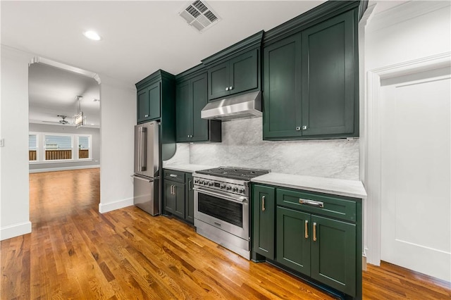 kitchen featuring backsplash, light hardwood / wood-style floors, stainless steel appliances, and green cabinetry