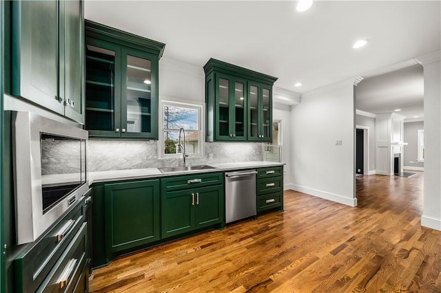 kitchen with hardwood / wood-style floors, green cabinets, crown molding, sink, and appliances with stainless steel finishes