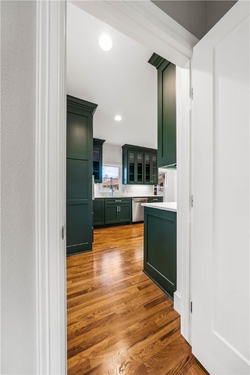 kitchen with dishwasher, hardwood / wood-style floors, green cabinets, and sink