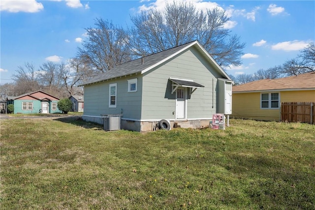 rear view of property featuring a lawn, cooling unit, and fence