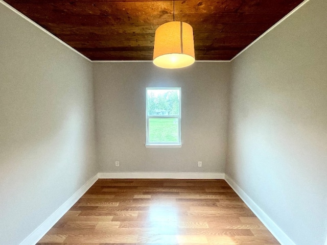 unfurnished room with ornamental molding, wooden ceiling, wood finished floors, and baseboards